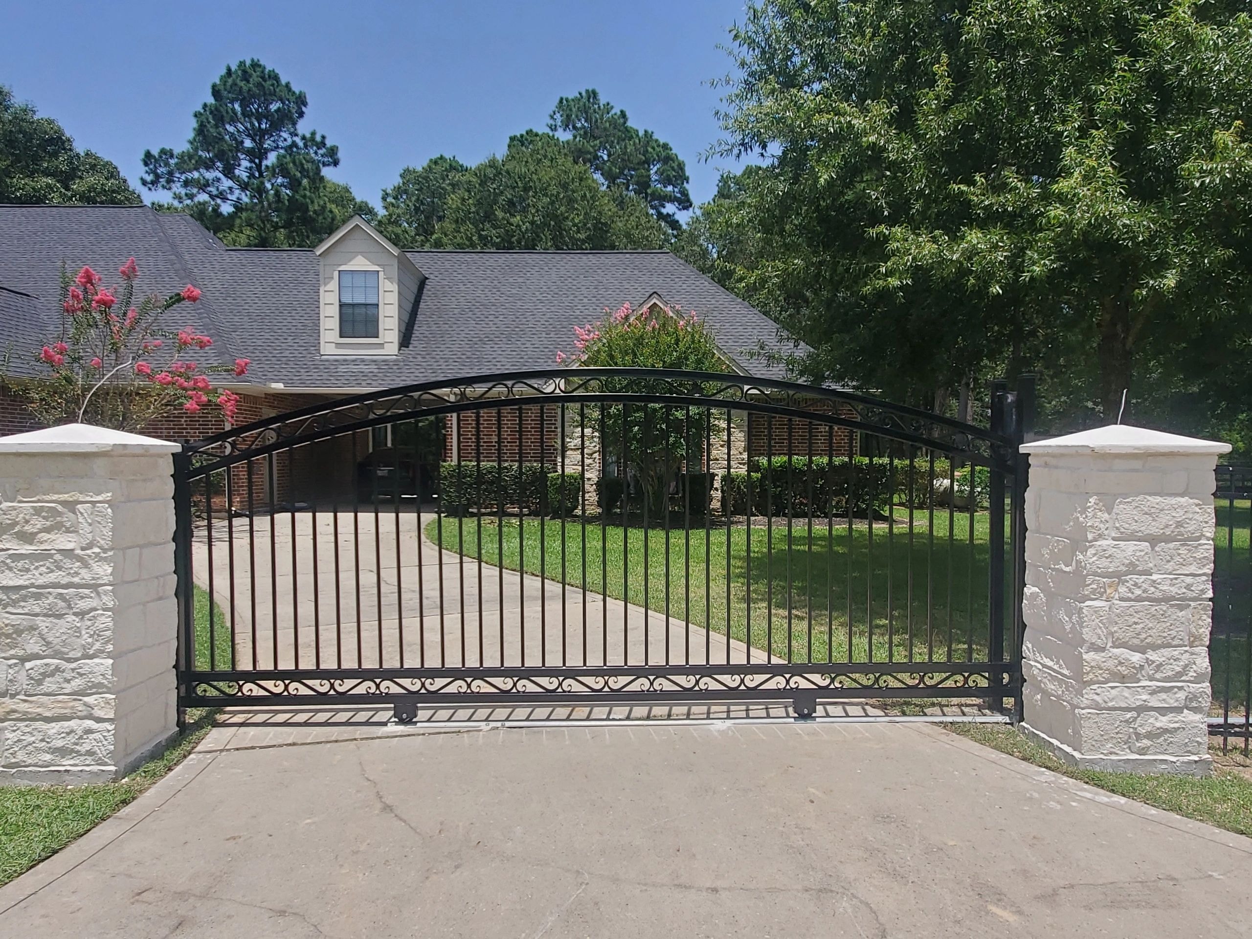 Ornate black driveway gate brick home